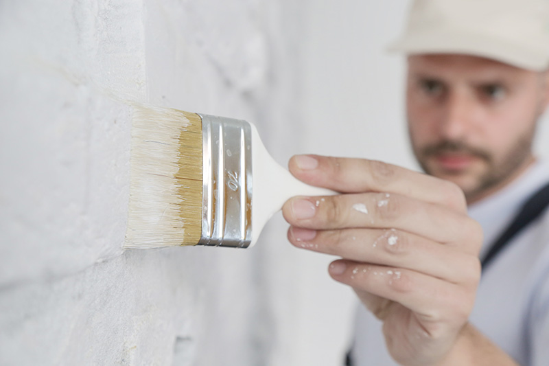 Maler mit Pinsel pinselt eine Wand